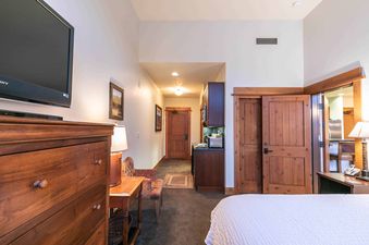 A hotel bedroom with a large wooden dresser and a flat screen TV on the wall.