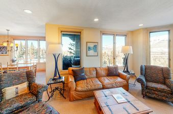 Lorian 14 is a condo with a large leather sofa and a coffee table in the living room, featuring views of the mountains from windows.