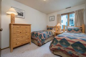 Two twin log beds with patterned bedding in the cozy guest room at Whiteridge B5.