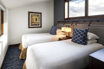 A modern and bright bedroom in the Teton Mountain Lodge and Spa Two Bedroom Bi-Level Suite featuring two twin beds.
