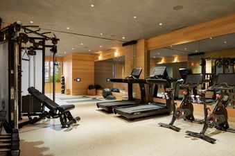 A modern fitness studio with treadmills, stationary bikes, and strength training equipment.