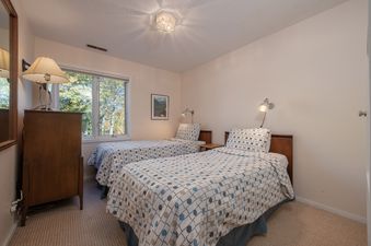 Cozy guest bedroom in Whiteridge B1 with two twin beds and a window showcasing outdoor trees.