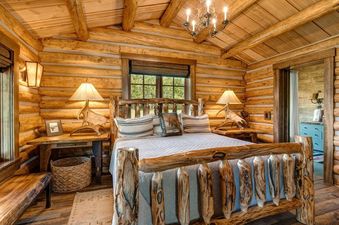 Rustic bedroom with log walls, log bed, and antler lamps at 7 Cabins Jackson Hole.