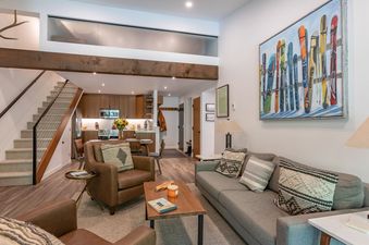A spacious living area within Whiteridge B7 features a gray sofa, two leather armchairs, and a wooden coffee table, all centered on a neutral rug.