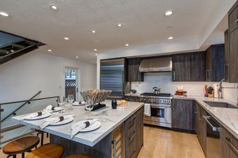 The gourmet kitchen in Abode at Pick N Shovel features top-of-the-line stainless steel appliances and a large marble island with seating.