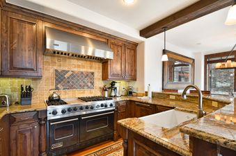 A spacious, modern kitchen with rich wooden cabinetry, granite countertops, and stainless steel appliances.