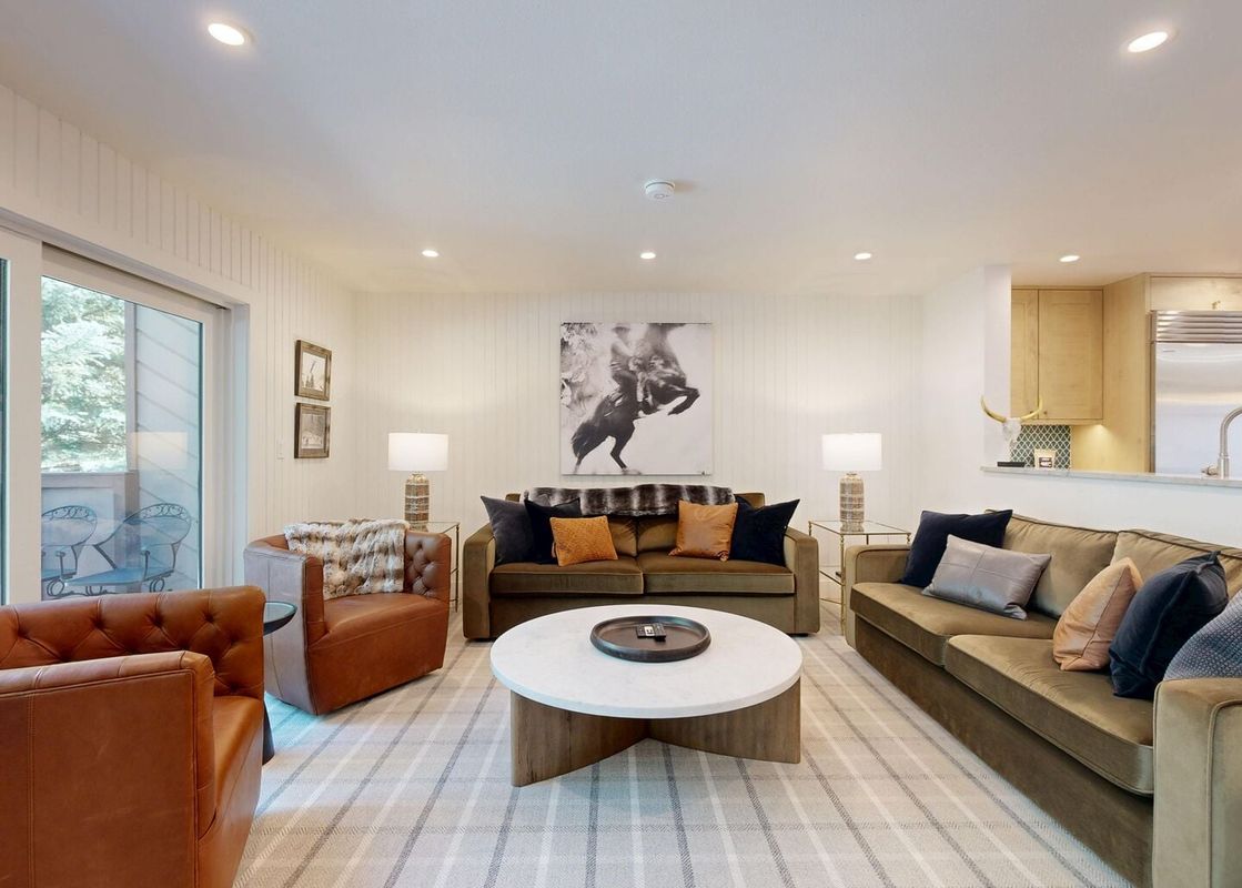 Comfortable living room with plush sofas, leather armchairs, and a large plaid rug in Windriver 2.