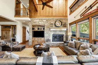 The living area of Deer Valley Lookout 26 features high ceilings, a stone fireplace, and comfortable sofas, creating a welcoming and spacious atmosphere.